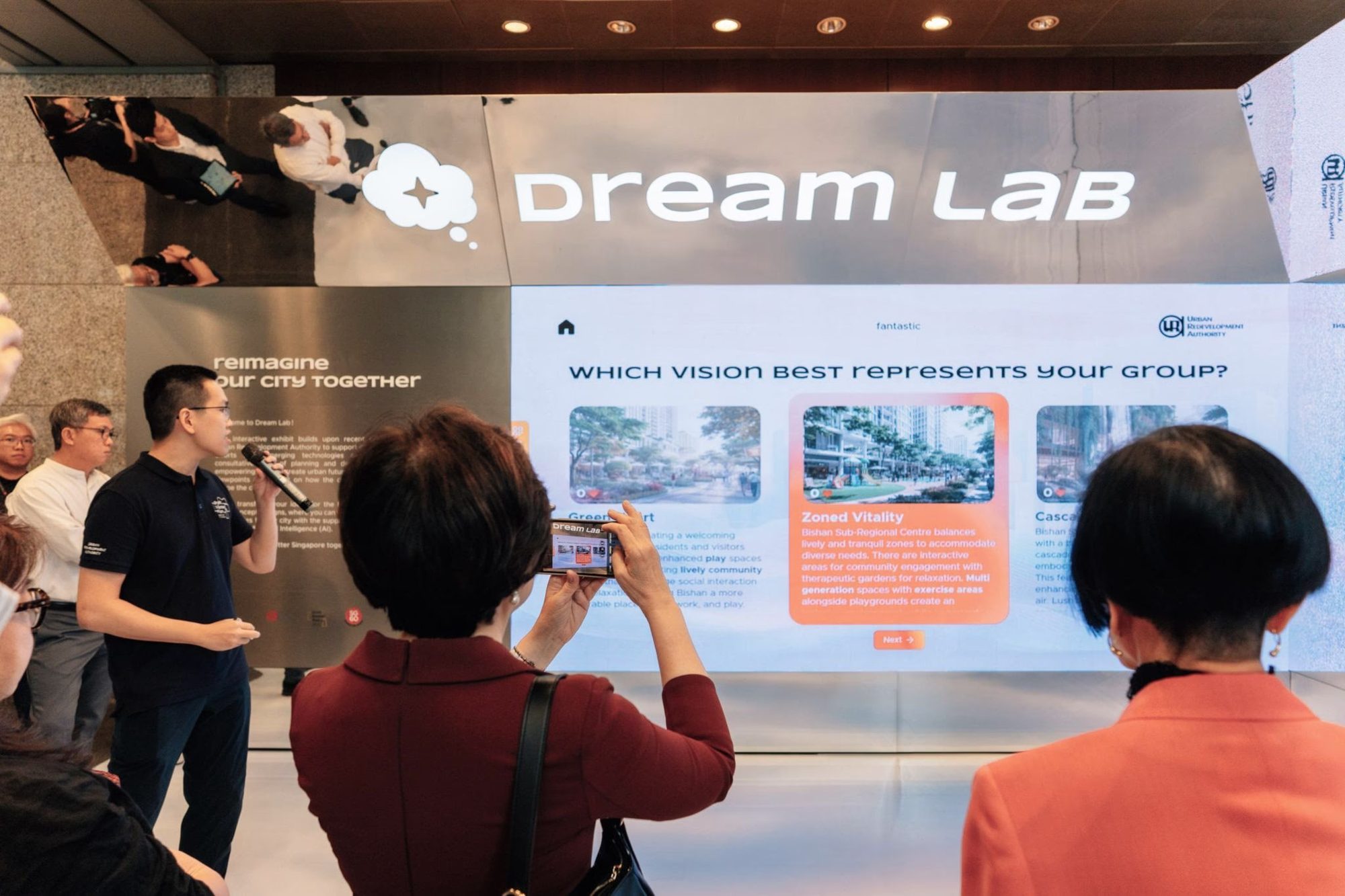 Launch day: the host presenting the voting wall to visitors as one guest photographs the AI-generated vision options.