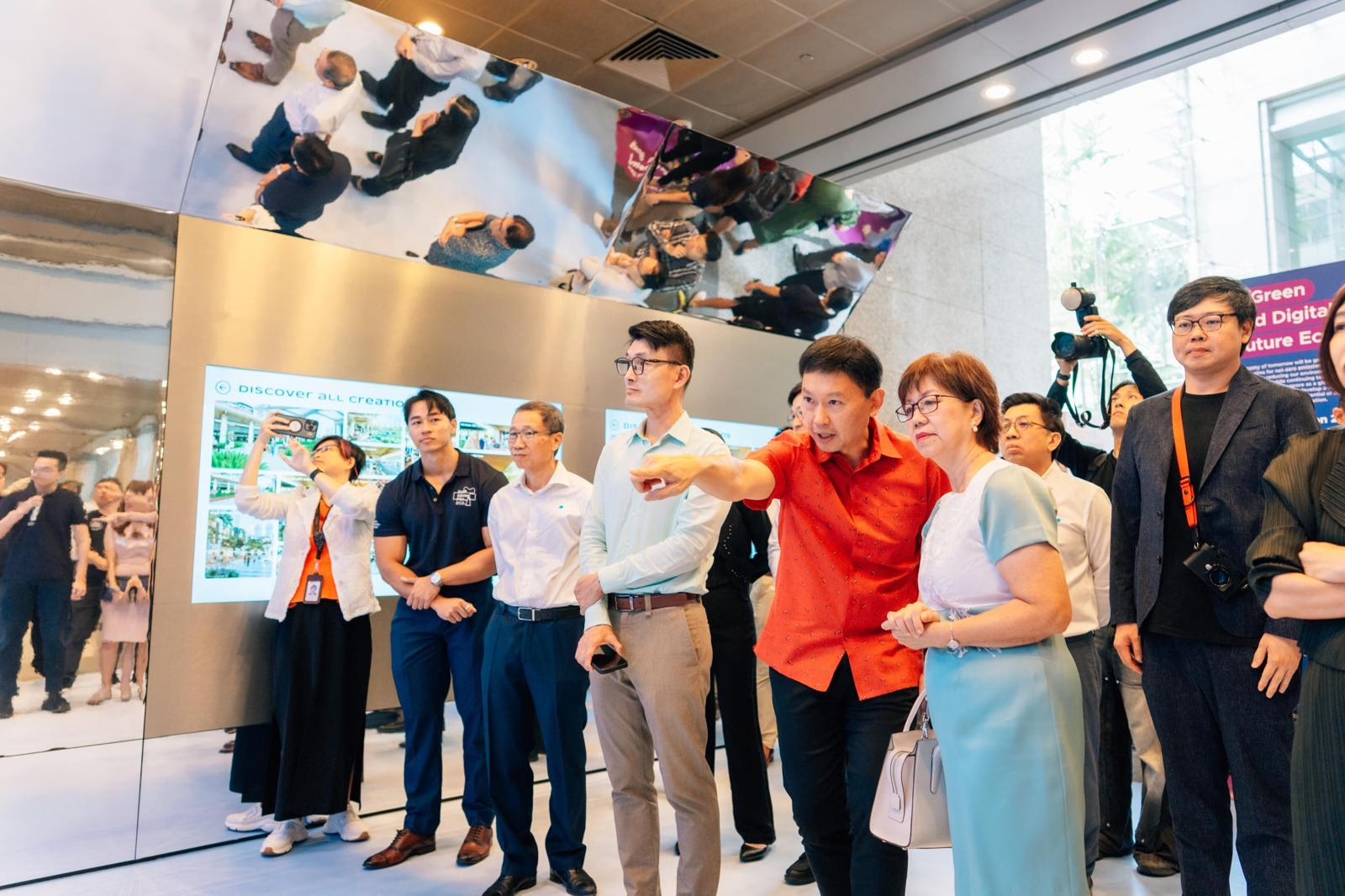 The guest of honour touring the Dream Lab exhibition at launch, engaging with the wall of AI-generated creations as officials, guests and media look on.